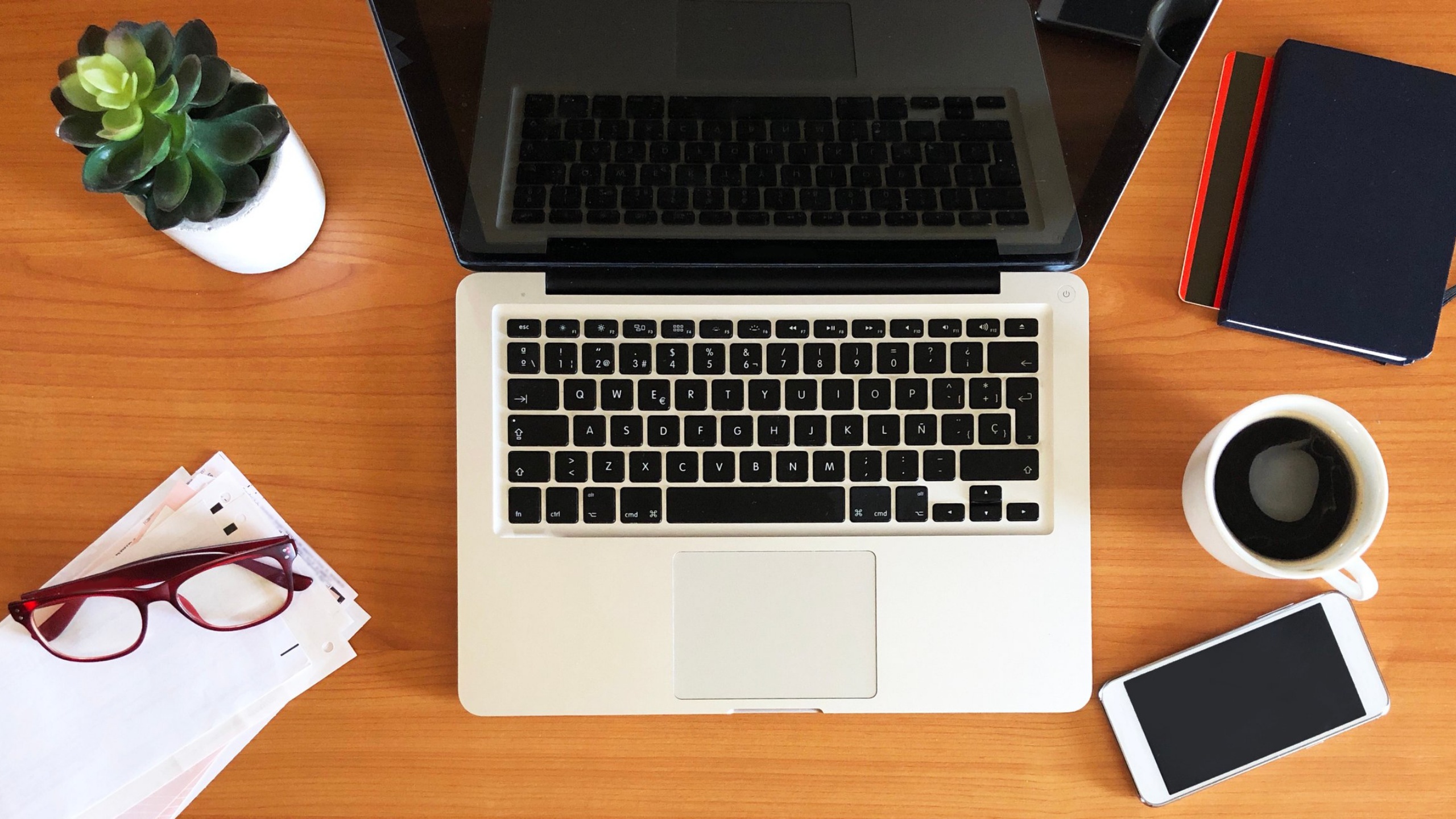 Freelancer's desk—clean, with a nice mug, a laptop, a plant, and maybe a scattered pile of receipts to one side